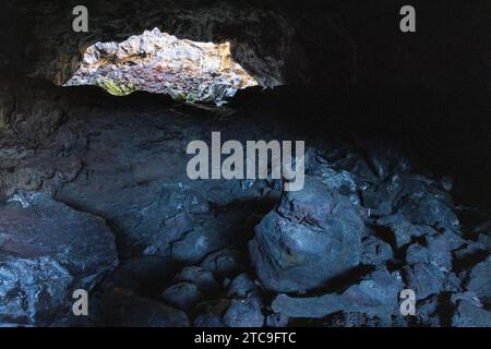 Une ouverture de grotte dans Indian tunnel s'élevant au-dessus des rochers le long du plancher de la grotte. Craters of the Moon National Monument, Idaho Banque D'Images