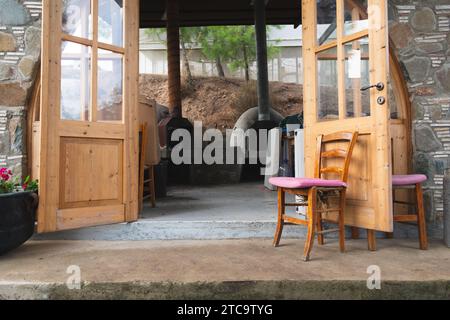 Une porte ouverte en bois blanc avec une chaise assortie positionnée devant elle, à l'extérieur d'un immeuble résidentiel Banque D'Images