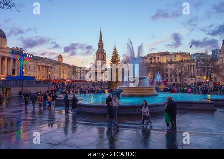 Londres, Angleterre, Royaume-Uni - 10 décembre 2023 : spectaculaire Sunset Gathering : scène de Noël animée de Trafalgar Square capturée au milieu de la fontaine et NAT Banque D'Images