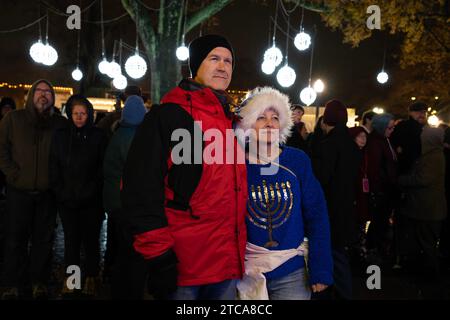 Marietta, Géorgie, États-Unis. 10 décembre 2023. Ben et Louise Probst de Smyrna regardent la quatrième bougie allumée sur une grande menorah à Glover Park dimanche, célébrant la quatrième nuit de Hanoukka. (Image de crédit : © Robin Rayne/ZUMA Press Wire) USAGE ÉDITORIAL SEULEMENT! Non destiné à UN USAGE commercial ! Banque D'Images