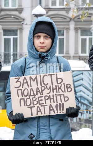 Un garçon avec une affiche «au lieu de cadeaux, retournez mon père» se tient au centre de Lviv. Les parents et les amis des soldats capturés du régiment 'Azov' participent à l'action entièrement ukrainienne 'ne vous taisez pas! Capture tue ! L'Ukraine attend que ses héros rentrent chez eux", à Lviv, Ukrain?. Ils se sont réunis pour rappeler les défenseurs capturés de Marioupol, qui sont en captivité russe depuis 19 mois et y sont torturés. Dans le même temps, une telle action a eu lieu dans de nombreuses villes d'Ukraine. Banque D'Images