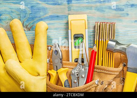 Ceinture à outils en cuir avec des outils de construction sur une planche de bois vue du dessus Banque D'Images