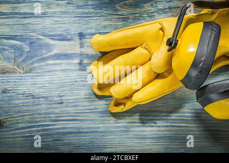 Gants de protection en cuir cache-oreilles sur planche de bois concept de construction Banque D'Images