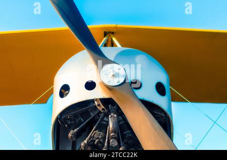 Hélice avec moteur et ailes jaunes d'un avion vintage sur un fond bleu en gros plan Banque D'Images