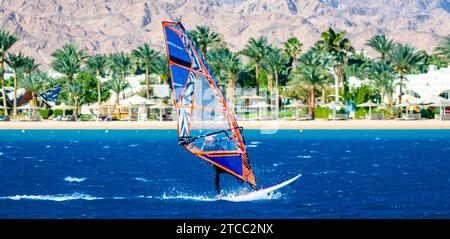 Windsurfer monte sur le fond de la plage avec un hôtel et des palmiers en Egypte Dahab Banque D'Images