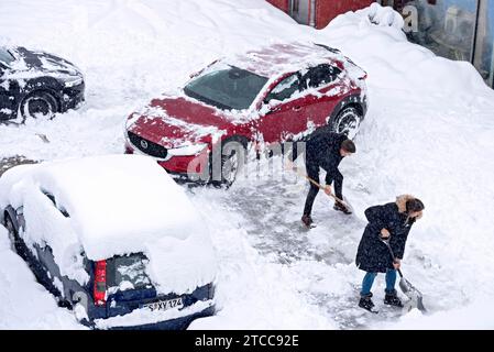 Homme et femme pelletant la neige sur le parking, voiture, voiture, neige fraîche, fortes chutes de neige, masses de neige, chaos de neige, pelle à neige, début de l'hiver Banque D'Images