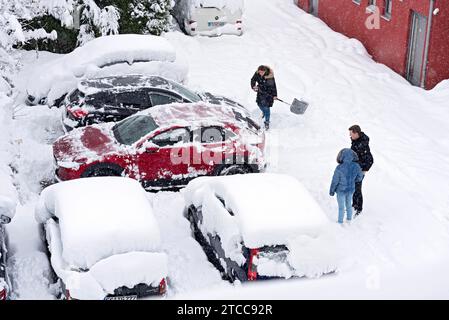 Femme pelletant la neige sur le parking, voiture, voiture, neige fraîche, fortes chutes de neige, masses de neige, chaos de neige, pelle à neige, début de l'hiver, Marzling Banque D'Images