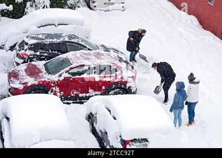 Homme et femme pelletant la neige sur le parking, voiture, voiture, neige fraîche, fortes chutes de neige, masses de neige, chaos de neige, pelle à neige, début de l'hiver Banque D'Images