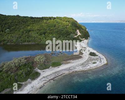 Une scène de plage tranquille avec une étendue d'eau calme de l'océan à l'horizon, plage de sable blanc et quelques arbres près du rivage, Corfou, Grèce Banque D'Images