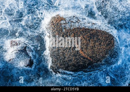 Rivage hivernal avec eau glacée, roches gelées et pierres en Suède Banque D'Images