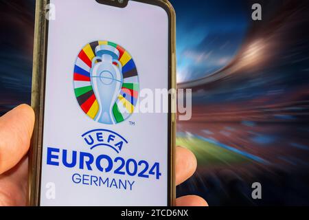 Image symbole UEFA-EURO 2024 : smartphone avec le logo EURO devant un stade complet Banque D'Images