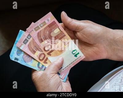 Mains d'une vieille femme tenant de petits billets d'euros. Vue de dessus Banque D'Images