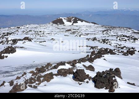 Champ de lave enneigé, roches volcaniques et cratère inactif sur le cratère Nord-est de l’Etna en hiver, Sicile, Italie Banque D'Images