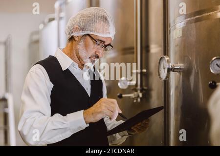 Viticulteur professionnel travaillant dans une grande usine de vinification moderne alcool alcool alcool industrie du contrôle de la qualité et de la fermentation surveillent la couleur vintage à Banque D'Images