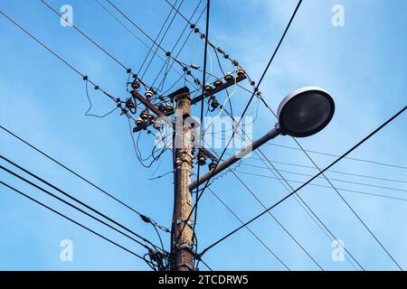 Lampadaire avec poteau électrique et fils électriques désordonnés, vue à faible angle Banque D'Images