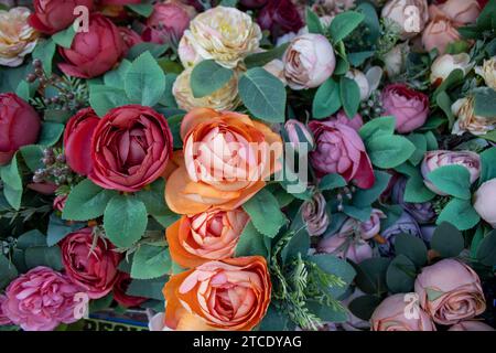 Une main féminine tient un paquet de fleurs vibrantes et variées, y compris des roses, des marguerites et d'autres fleurs Banque D'Images