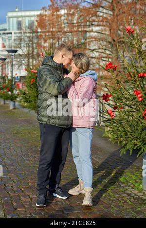 Portrait de jeunes gens attrayants, couple charmant bénéficiant de l'atmosphère chaleureuse sur la foire dans la veille de Noël. Passer du temps ensemble. Concept de trad nationale Banque D'Images