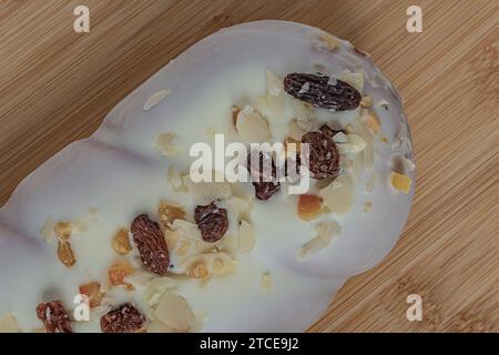 rouleau de coquelicot dans un glaçage blanc avec des raisins secs sur un fond blanc Banque D'Images