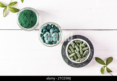Trois bocaux en verre avec du produit organique de spiruline d'algues vertes en comprimés, capsules, poudre. Une alternative à la médecine. Vue de dessus. fond blanc Banque D'Images