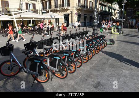 Plusieurs vélos électriques garés soigneusement dans une rangée dans la rue près du Teatro Massimo dans le centre-ville de Palerme Banque D'Images