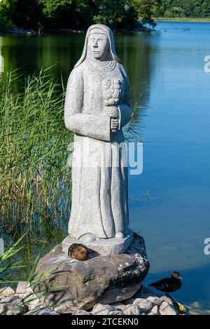 La belle nonne de la Wutzsee sur la rive de la Wutzsee au soleil. Il y a un canard sur le côté. La figure est faite de pierre grise. Banque D'Images