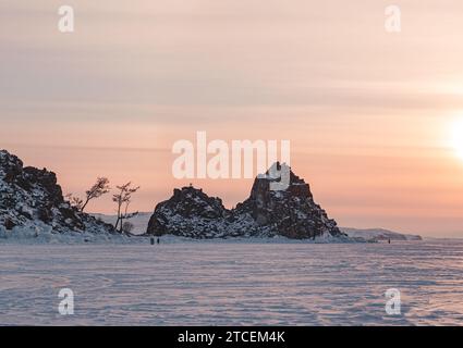 Shamanka rocher sur l'île d'Olkhon au coucher du soleil. Paysage hivernal du lac Baïkal. Lieu touristique célèbre sur le Baïkal Banque D'Images