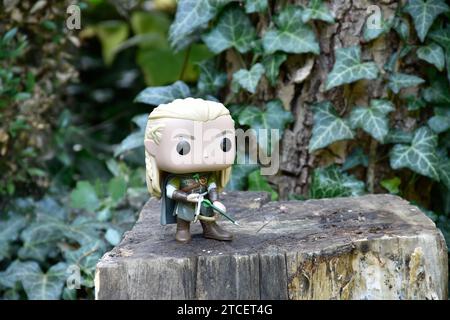 Funko Pop figurine d'action d'elfe Legolas du film fantastique le Seigneur des anneaux. Guerrier tenant arc et flèche. Arbre forestier, feuilles de lierre vert. Banque D'Images