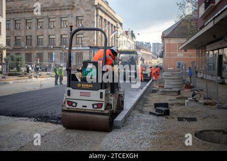 Belgrade, Serbie, le 9 décembre 2023 : rouleau à double tambour et machine à asphalte posant de nouveaux asphaltes le long de la rue en cours de reconstruction Banque D'Images