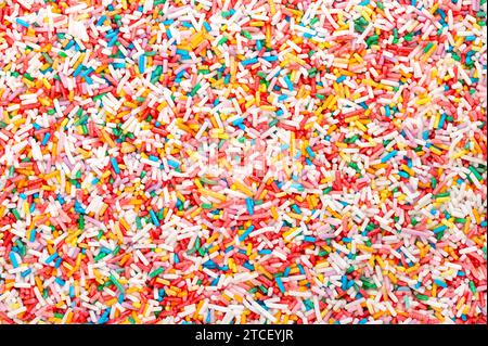 Arrosserie arc-en-ciel, fond et surface. Saupoudreuses de sucre colorées en forme de tige. Petits bonbons dans une variété de couleurs, utilisés comme décoration et garniture. Banque D'Images