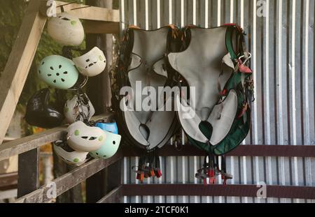 Équipement d'escalade - casques colorés et gilets de sécurité accrochés à une planche dans un parc de corde en gros plan Banque D'Images