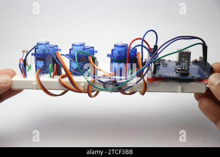 Micro servos de type à engrenages en plastique sur une carte d'expérimentation connectée à la carte de micro-contrôleur programmable sur fond blanc Banque D'Images