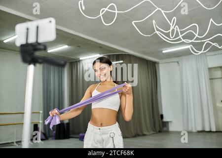 charmante danseuse afro-américaine dans la formation de sportswear blanc avec des élastiques dans le studio moderne Banque D'Images