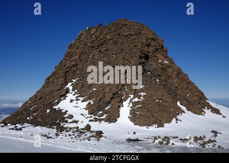 Champ de lave enneigé avec un hornito à flanc de montagne du cratère Nord-est de l'Etna, Sicile, Italie Banque D'Images