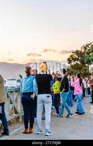 Touristes prenant des photos à Santa Monica, en Californie, au coucher du soleil avec les montagnes de Santa Monica en arrière-plan Banque D'Images