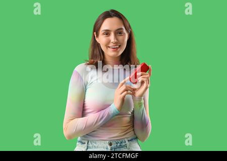 Jeune femme avec bloc de cigare électronique sur fond vert Banque D'Images