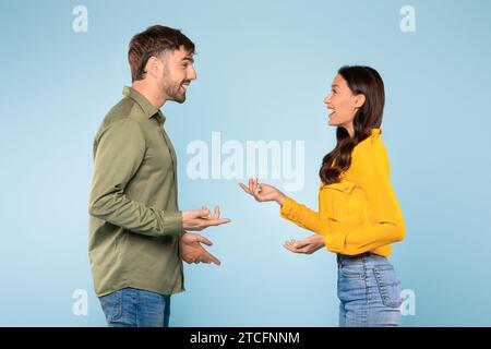 Homme et femme faisant des gestes dans la conversation, fond bleu Banque D'Images