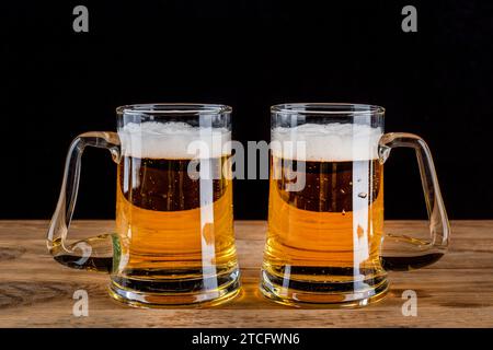 Deux tasses en verre avec de la bière sur fond sombre. Fond en bois. Banque D'Images