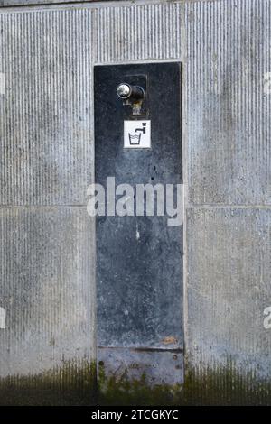 Petit robinet public pour l'eau potable sur fond de pierre bleue wtih signe d'eau potable et croissance moussue verte sur le sol et le mur en dessous Banque D'Images