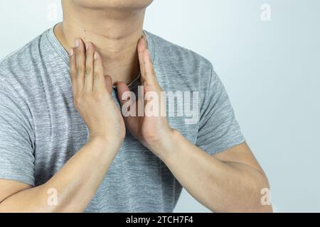 Homme asiatique touchant le cou avec la main parce qu'il souffre de mal de gorge Banque D'Images