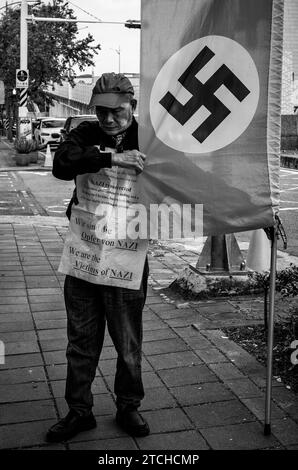 Taipei. 13 décembre 2023. Un manifestant se tient debout avec un drapeau arboré du symbole nazi devant l'école européenne de Taipei, Taiwan, le 13/12/2023, exigeant du gouvernement allemand d'honorer les obligations émises au Japon en réparation de la première Guerre mondiale La Old German Mark Association, composée de descendants de Taïwanais qui ont acheté ces obligations pendant la domination coloniale japonaise, affirme que malgré le refus des gouvernements allemand et japonais de racheter les obligations, leur valeur financière et historique reste selon Wiktor Dabkowski Credit : dpa/Alamy Live News Banque D'Images