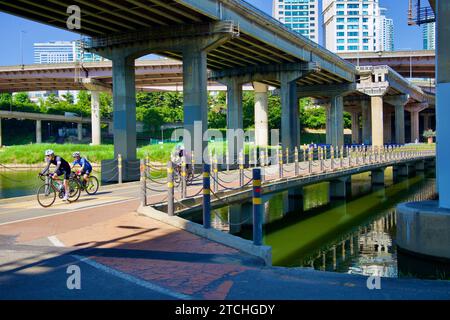 Séoul, Corée du Sud - 2 juin 2023 : les cyclistes traversent le pont sur Tan Stream, avec le quartier animé de Gangnam visible au-dessus du remblai et Banque D'Images