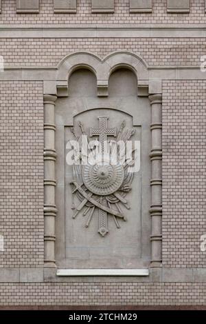 Bas-relief sur le mur de la maison en forme de croix et d'armes anciennes. Banque D'Images