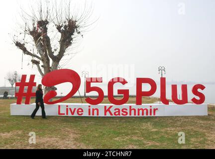 Bharti Airtel dévoile une technologie 5G de pointe 12 décembre 2023, Srinagar Cachemire, Inde : Une femme passe devant Airtel5Gplus sur les rives du lac Dal pendant une expérience 5G plus en direct à Srinagar. Airtel a annoncé le lancement de ses services 5G de pointe en octobre 2022 dans 8 villes en Inde. Aujourd'hui, les services d'Airtel sont en direct dans tous les États et territoires de l'Union de l'Inde avec plus de 50 millions de clients au 1 octobre 2023. Srinagar Kashmir India Copyright : xFirdousxNazirxxEyepixxGroupx Banque D'Images