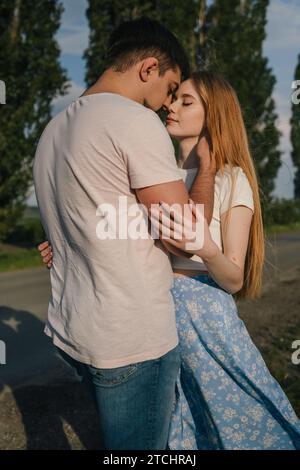 Couple marié aimant debout et frottant le nez touchant le front à l'extérieur dans la nature. Petite amie et petit ami. Rendez-vous romantique. Banque D'Images