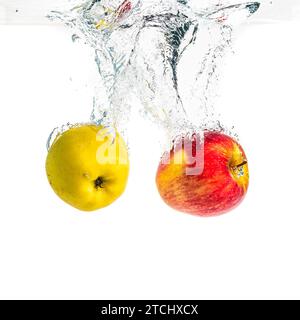 Pommes provoquant des éclaboussures d'eau et coulant avec des bulles d'air sur fond blanc. Nourriture saine Banque D'Images