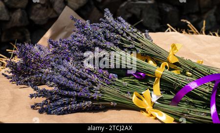 Des bouquets de lavande avec des rubans violets et jaunes reposent sur du papier kraft Banque D'Images