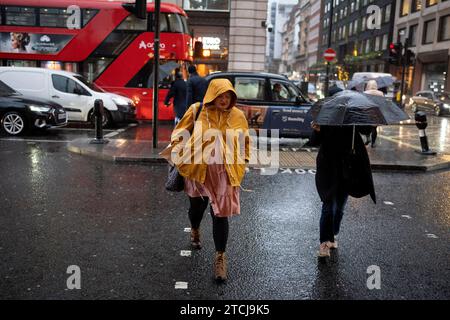 Les amateurs de Noël et autres piétons traversent Piccadilly par un après-midi pluvieux à Westminster, le 12 décembre 2023, à Londres, en Angleterre. Banque D'Images