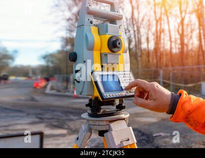 Ingénieur de chantier utilisant son instrument pendant les travaux routiers. Constructeur utilisant le tachymètre de station de positionnement total sur le chantier de construction pour le nouveau réglage de la route Banque D'Images