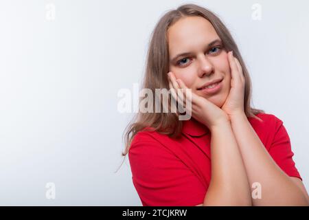 Jeune fille adolescente souriante vêtue d'un t-shirt rouge sur un fond blanc Banque D'Images