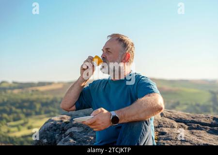 Homme barbu se détendant seul au sommet de la montagne et buvant un café chaud. Travel Lifestyle concept le parc national Peak District en Angleterre Banque D'Images